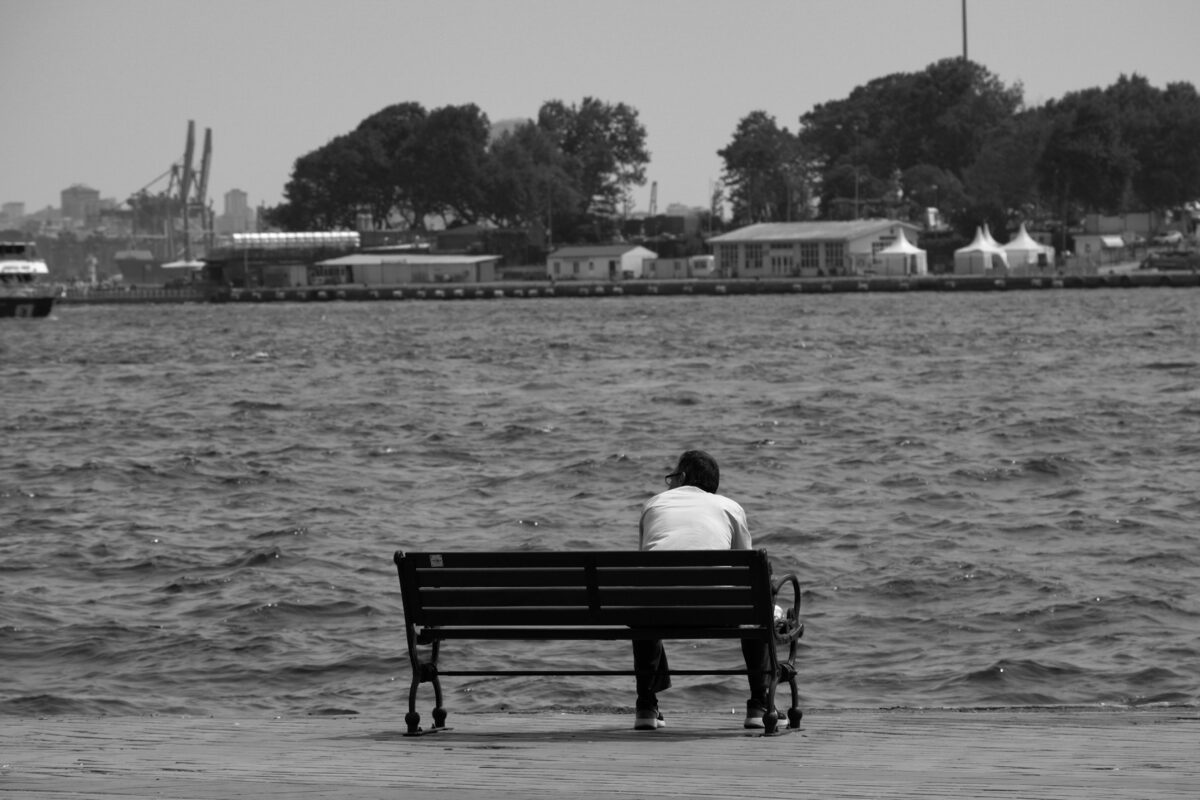 man-sitting-alone-on-beach-on-seashore