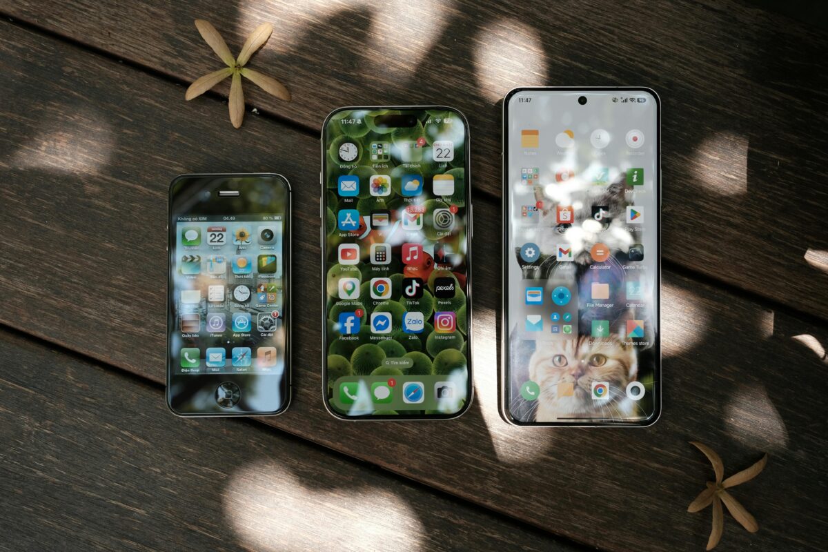 three-smartphones-displaying-home-screens-on-wooden-surface