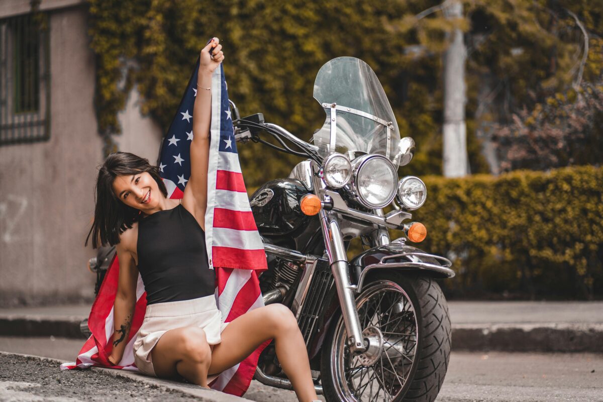 The American Pride Crisis Is No Longer Just Political Noise. 8 Reasons Why 2 a-woman-holding-a-flag-beside-a-motorcycle