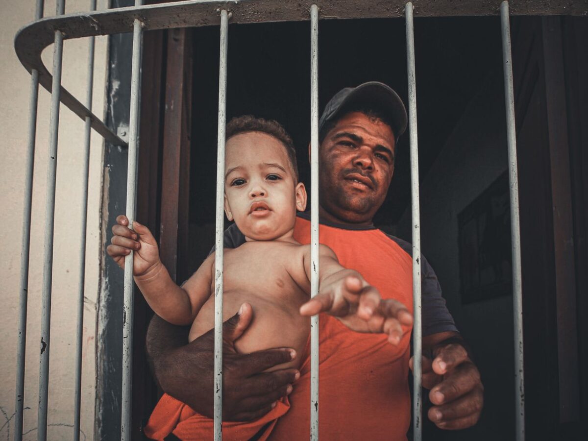 father-and-child-standing-behind-the-metal-railings-while-looking-at-the-camera-
