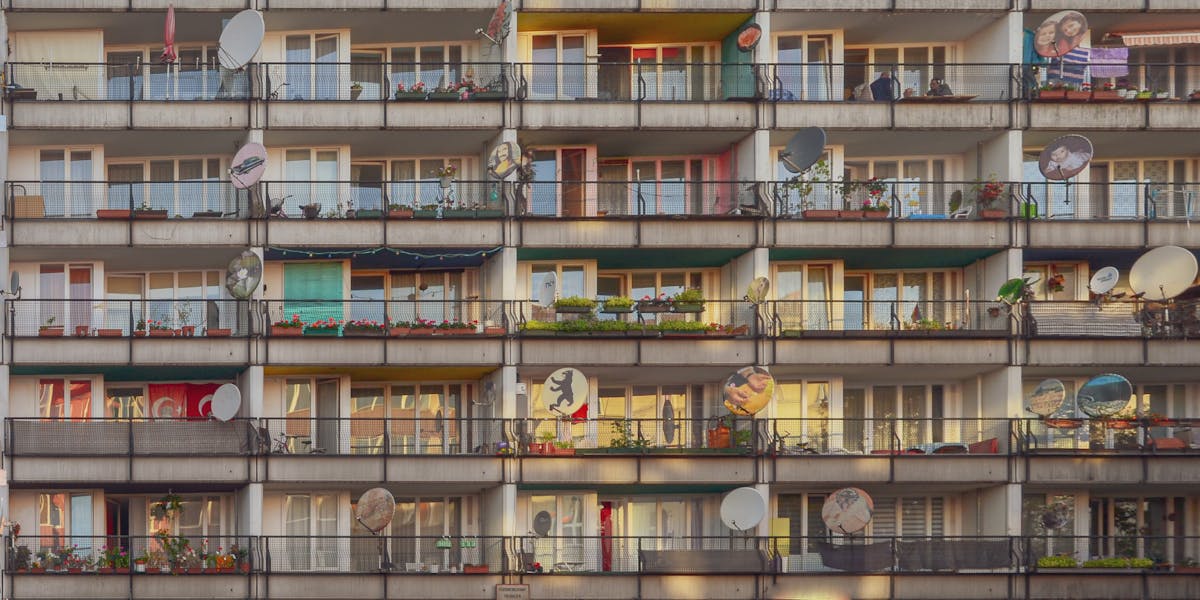 Photograph of a residential building with colorful balconies and satellite dishes in Berlin.