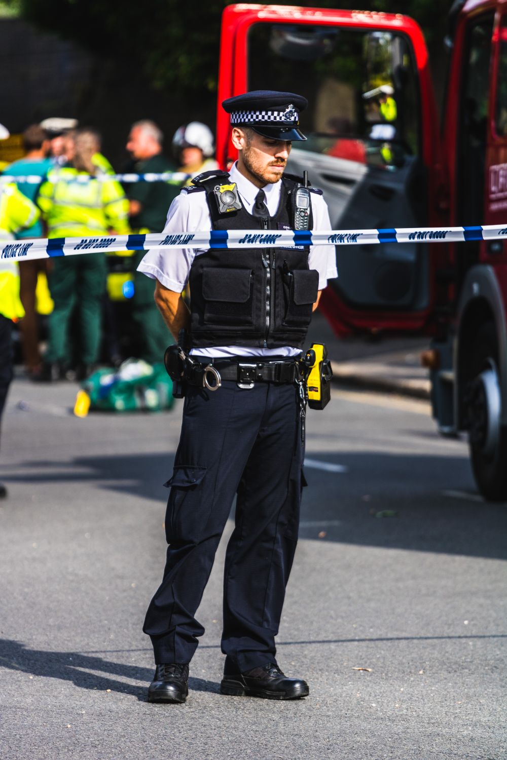 Police officer on duty securing a crime scene with barricade tape, ensuring public safety.