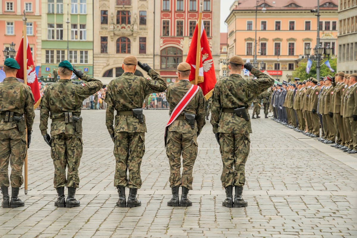 The Military Salute You’ve Been Misreading Your Whole Life 3 Polish soldiers saluting during a military parade in Wrocław city square, showcasing national pride.