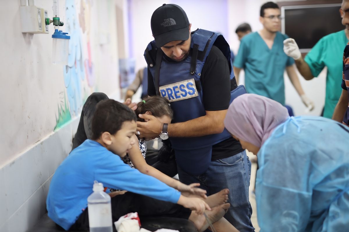 Press aiding children in medical facility alongside doctors and nurses.