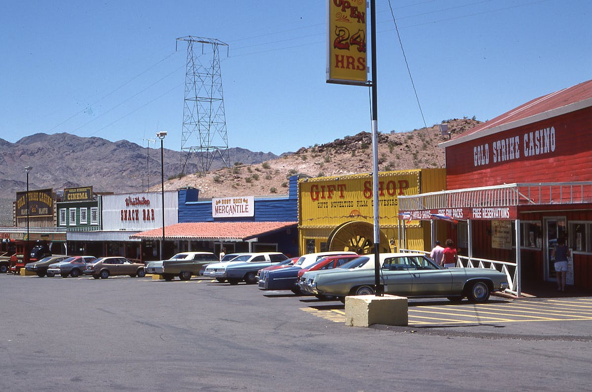 7 Most Miserable States to Live in America in 2026 3 Retro-style roadside shopping area with casino and parked cars under clear blue sky.