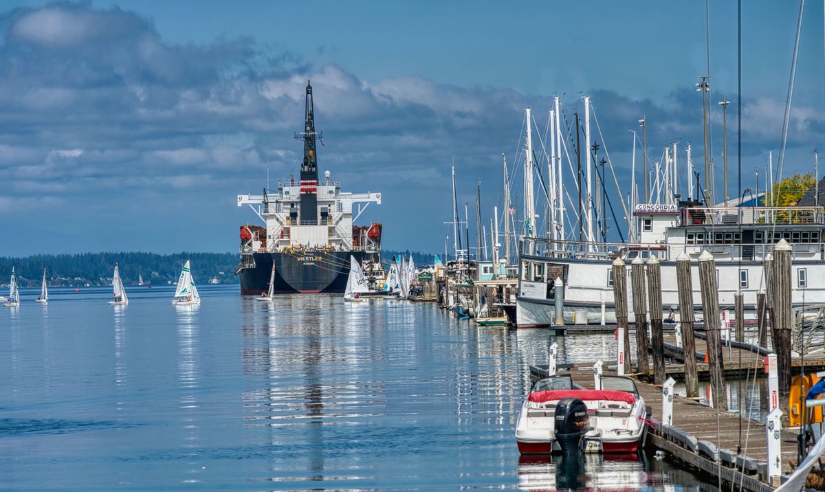 Sailboats and cargo ship at Olympia Harbor, Washington, on a calm sunny day.