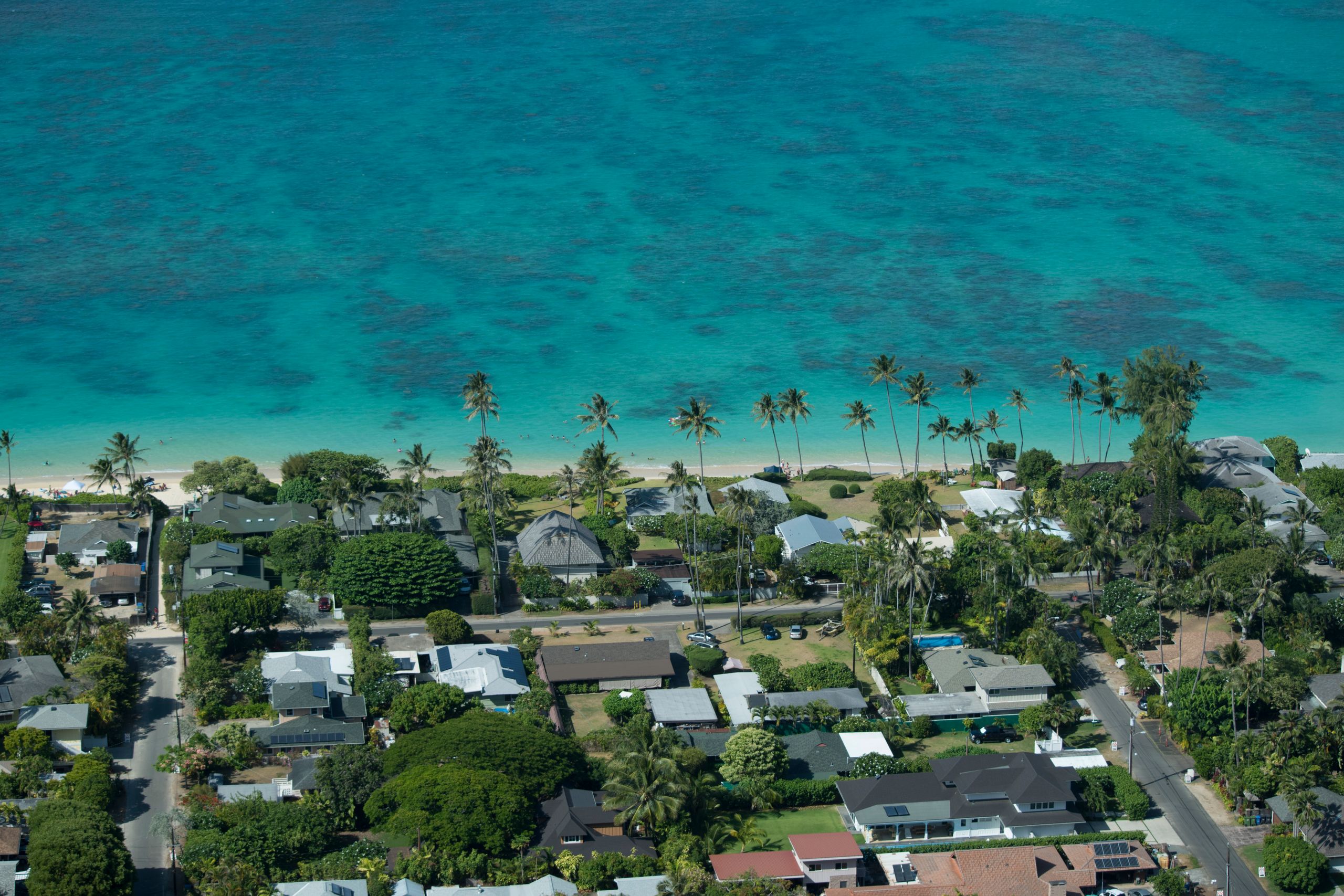 Scenic aerial view capturing Kailua's coastal houses, lush greenery, and clear turquoise waters.