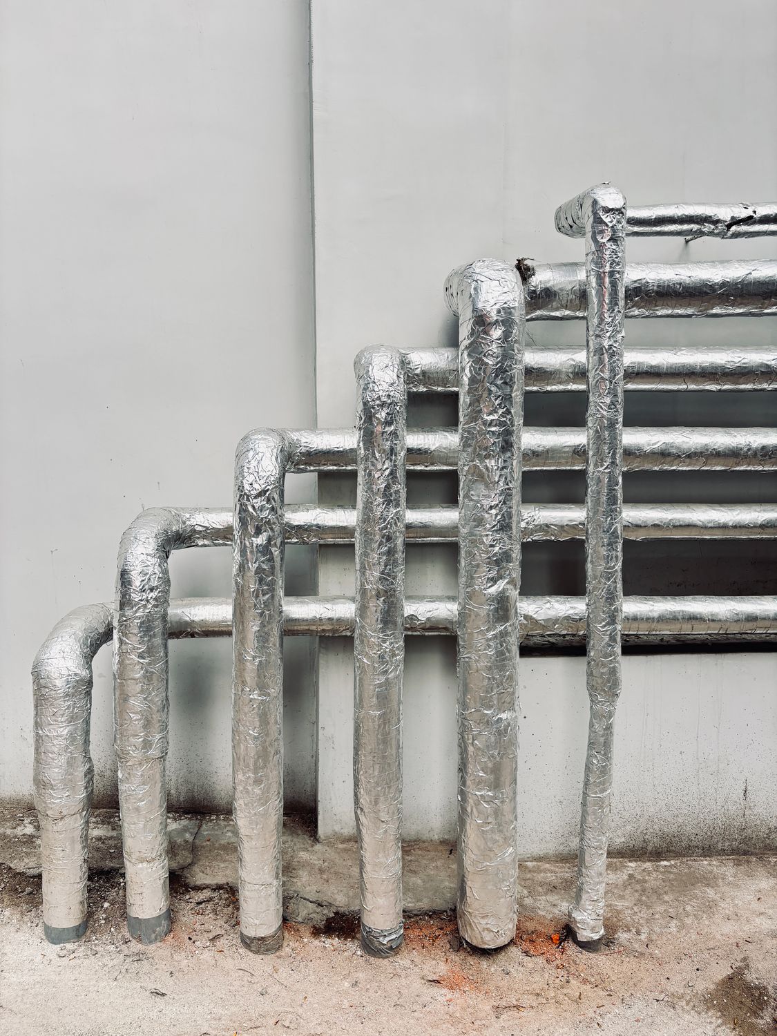The Winter Storm Mistake Too Many Families Make Before the Snow Even Starts 4 Silver insulated pipes arranged vertically on a building exterior, showcasing industrial architecture.