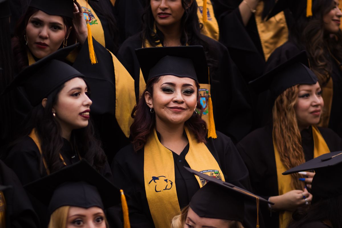 Smiling graduates in caps and gowns celebrate their accomplishments at a graduation ceremony.