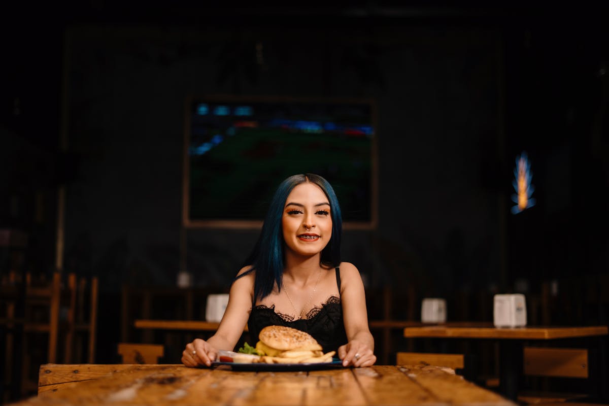 Wendy’s Branding Catastrophe: How the New Blue Makeover Risks Killing Appetite and Loyalty 1 Smiling woman with blue hair enjoying a burger at a cozy cafe setting.