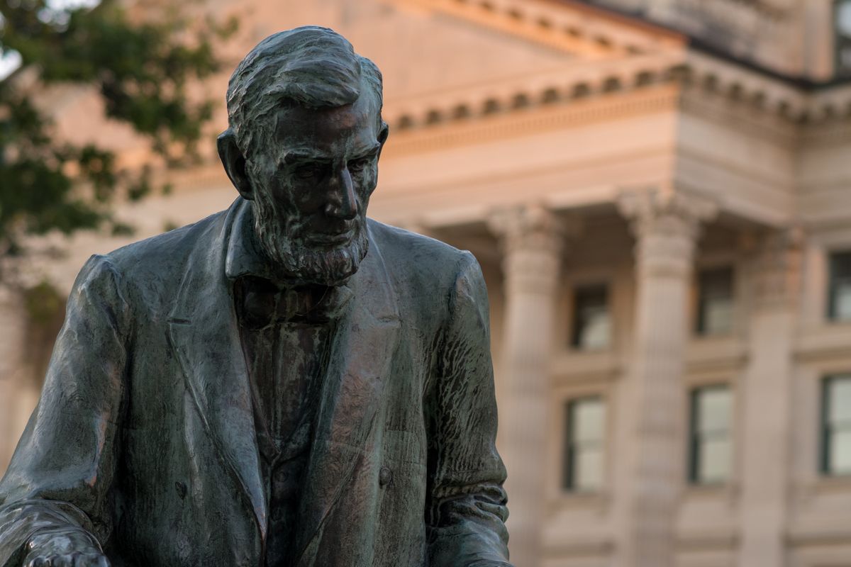 Statue of Abraham Lincoln with a historic architectural backdrop.
