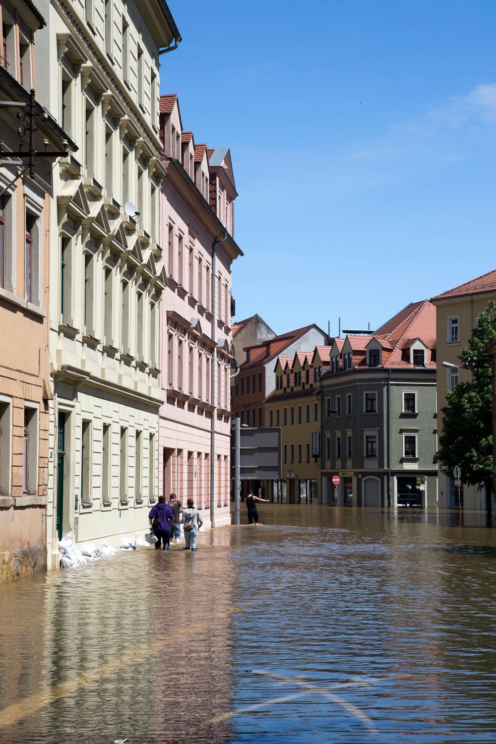 Street view of a flooded European city with people wading through water.