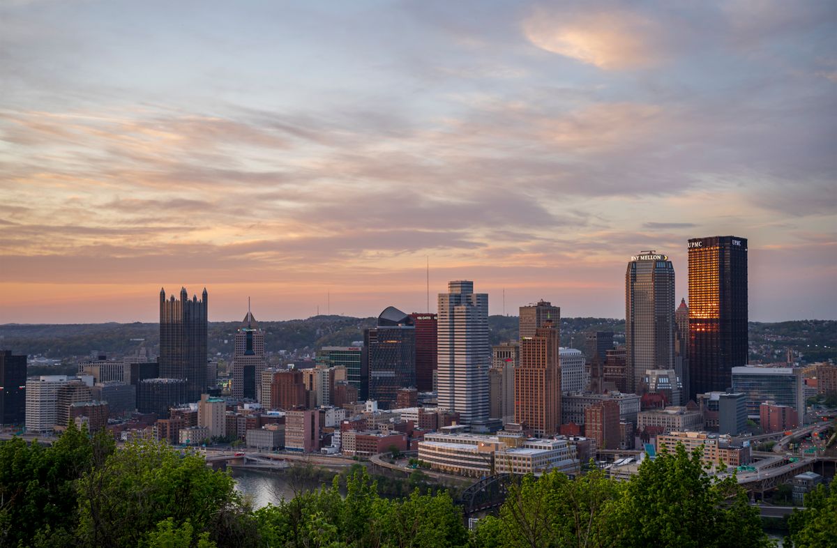 Stunning aerial view of Pittsburgh skyline with vibrant sunset colors in the sky.