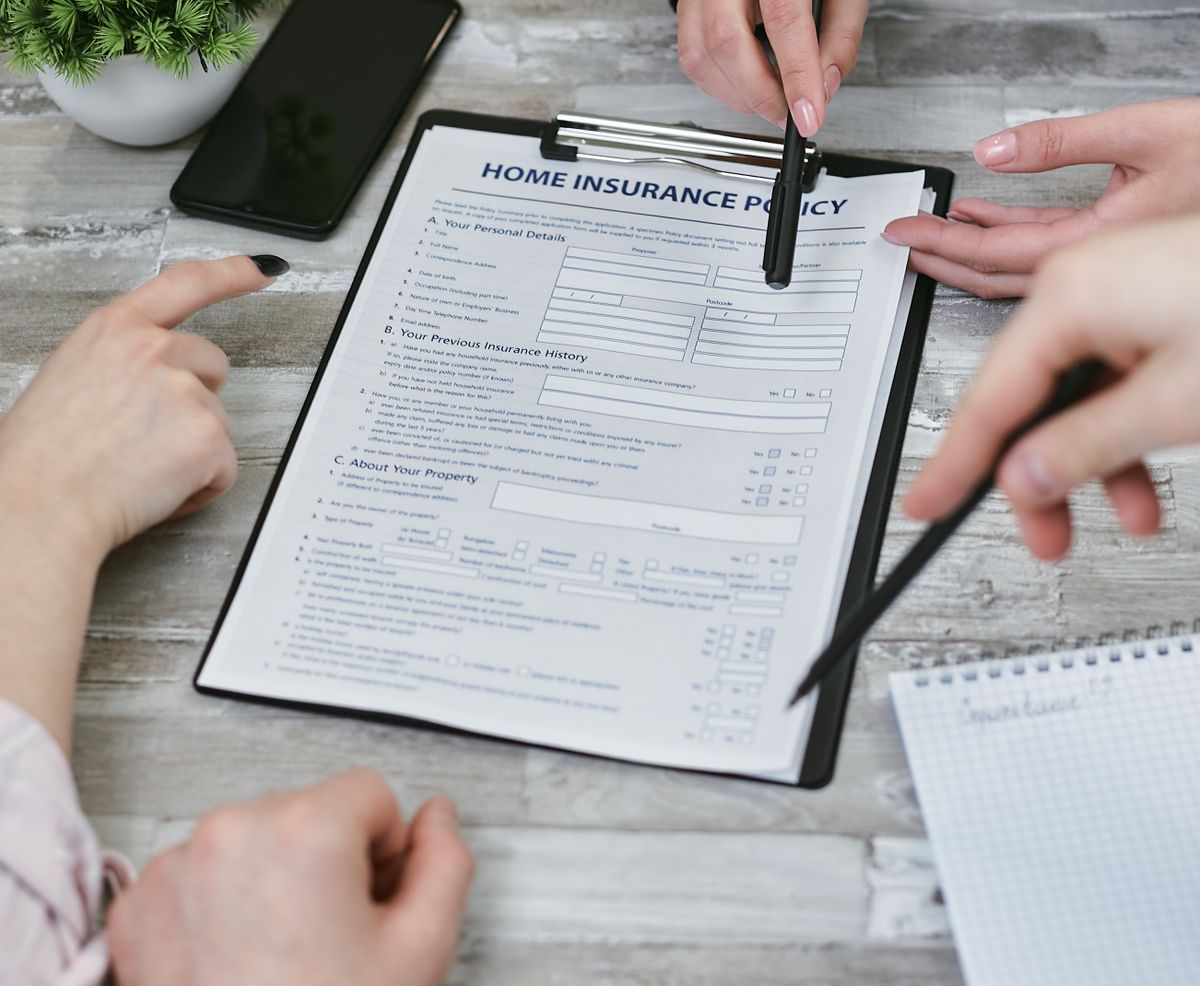 EU Long-Term Residence in Europe: The 5-Year Rule That Could Change Your Future in the EU 2 Three individuals collaborating on a home insurance policy document. Elements include a clipboard, notes, and pointing hands.