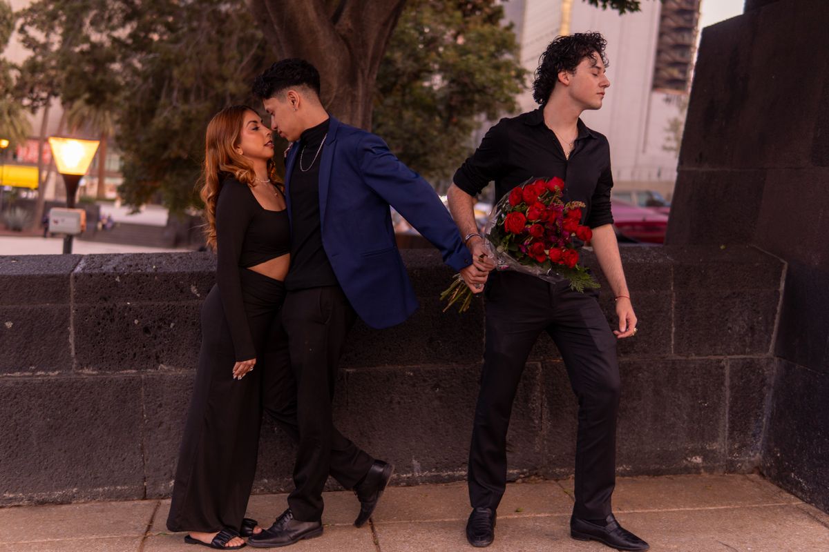 Three people caught in emotional love triangle outdoors at sunset.