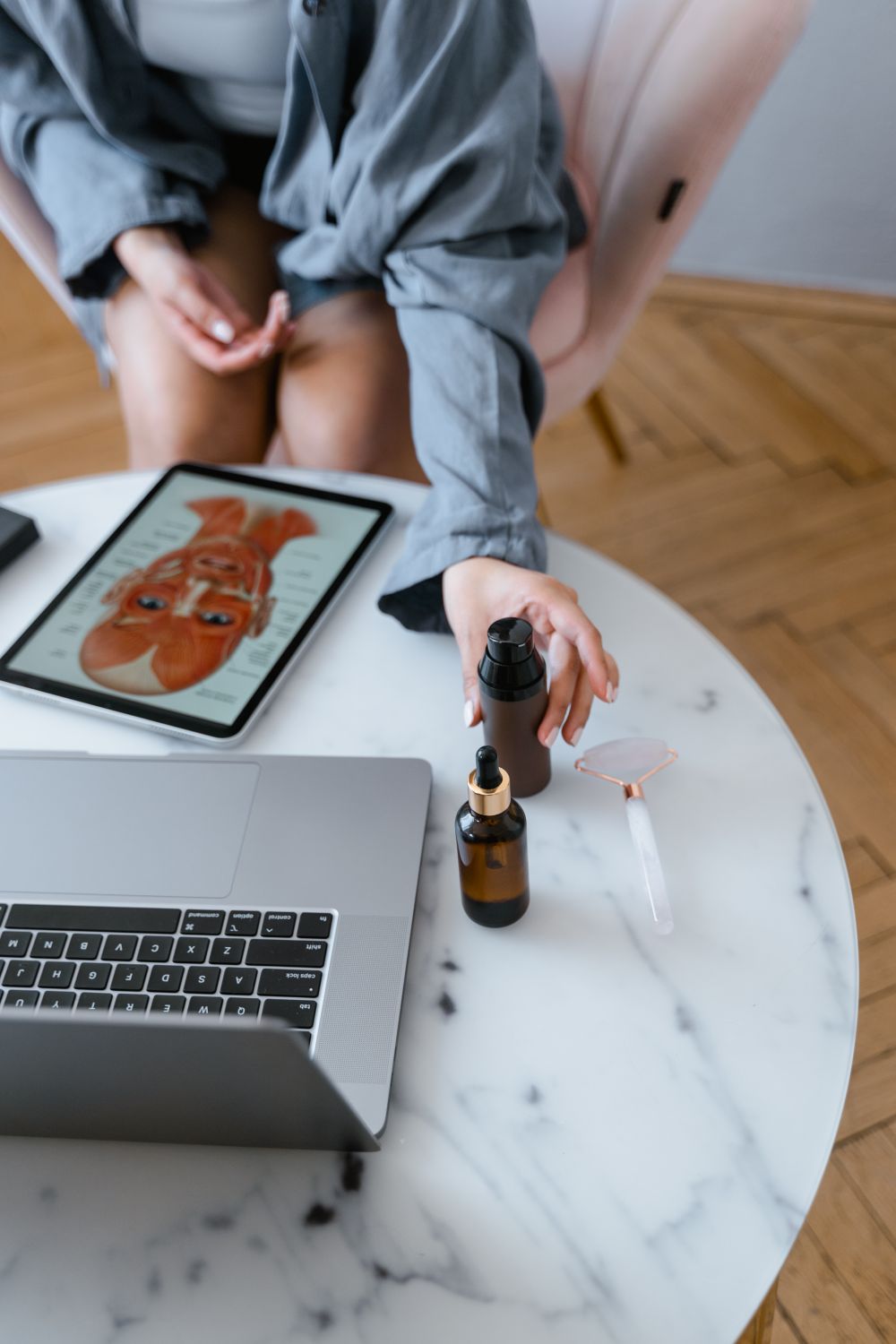 10 Small Business Website Examples That Show What High-Performing Websites Do Right 4 Top-down view of skincare products and jade roller on a table near a laptop and a tablet showing skincare routine.