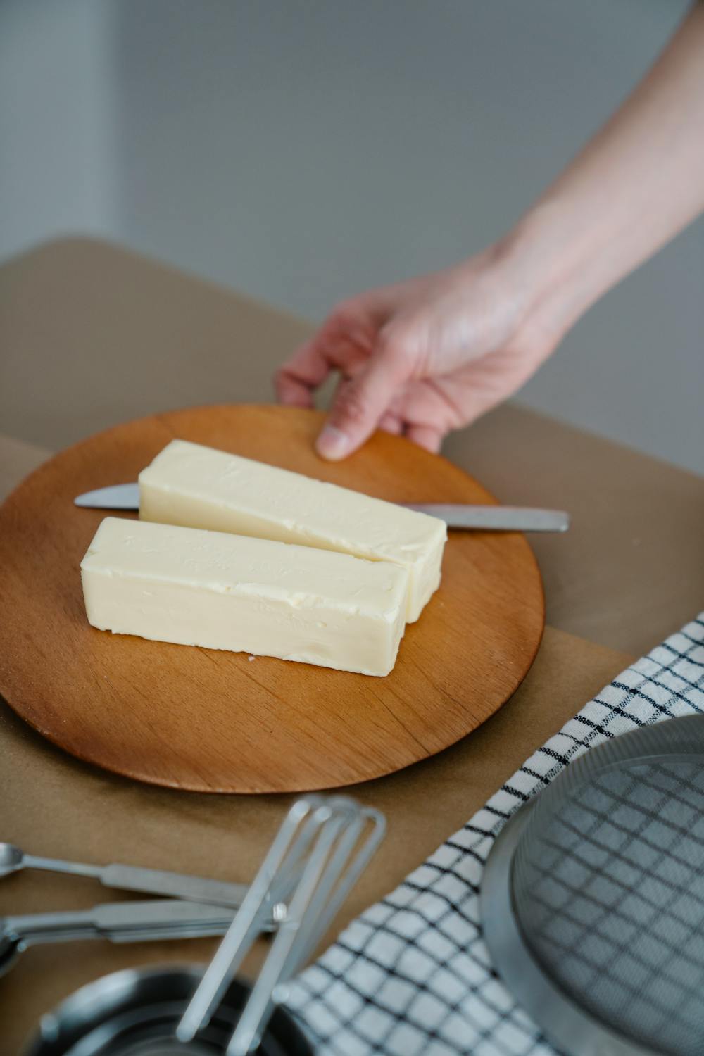 Two blocks of butter with a knife on a wooden plate, perfect for culinary content.