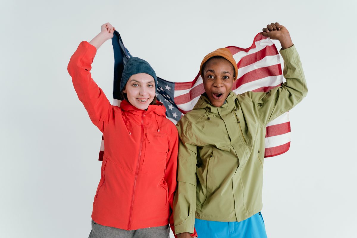 8 Ways the World Is Fed Up With Americans in 2026: A Global Backlash 4 Two friends joyfully holding an American flag, expressing friendship and celebration.