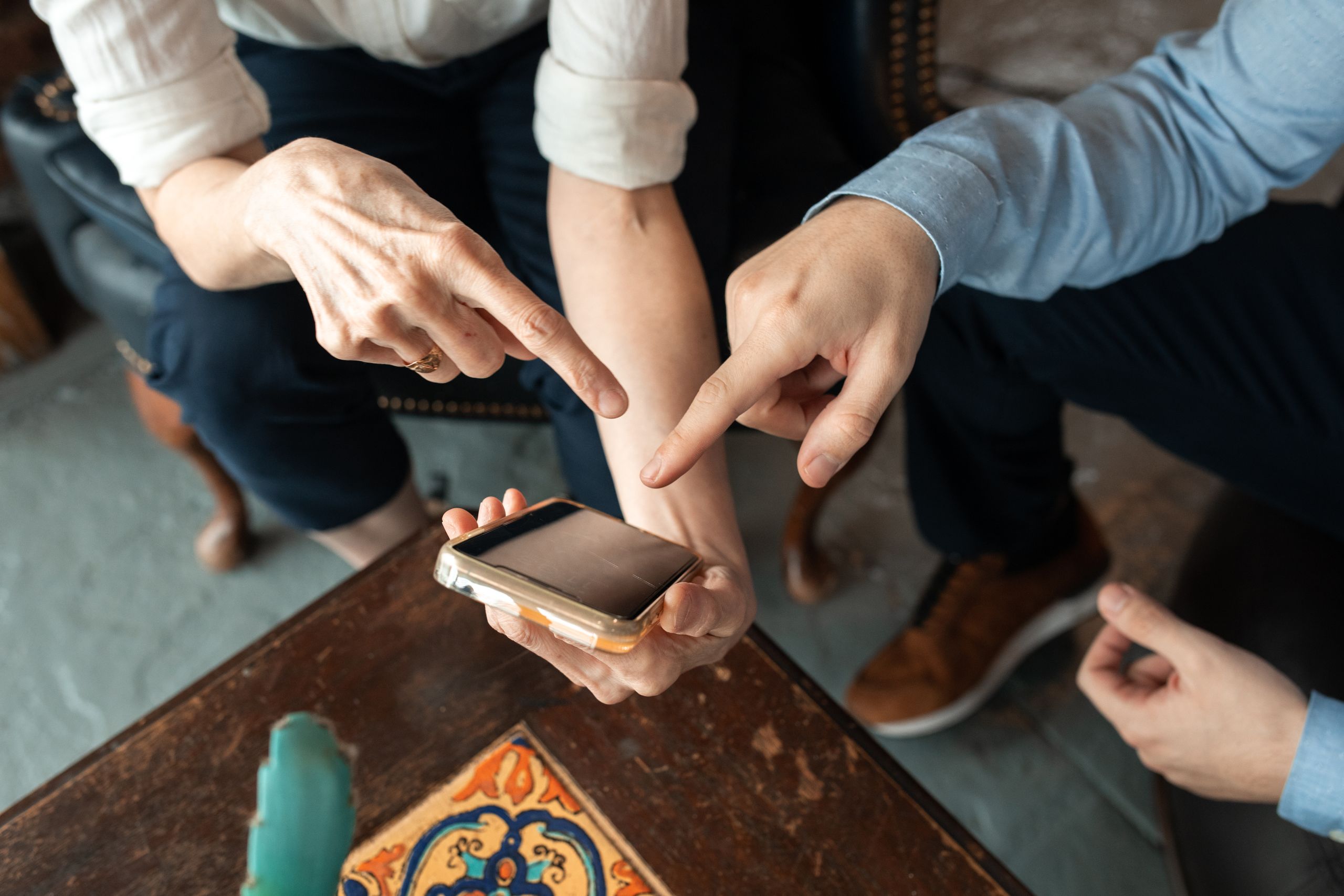 Kai Trump’s “My House” White House Comment Backfired Because American Taxpayers Know Who Really Pays For It 1 Two people engaged in discussion, pointing at a smartphone on a table indoors.