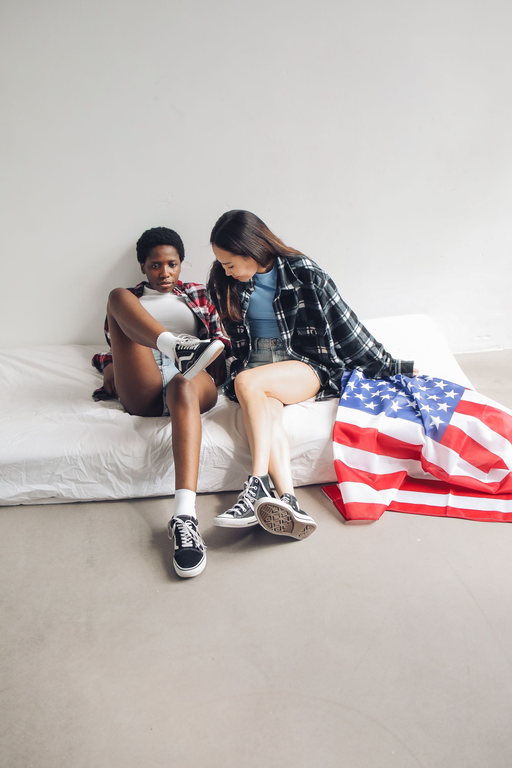 Millions of Americans Could Face a Social Security Shock by 2032, According to New Trustees Report 1 Two young friends relaxing in a room, draped with an American flag, showcasing a casual vibe.