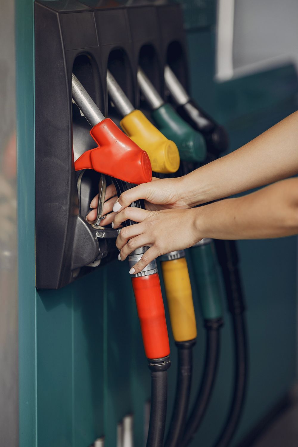 13 Gas Station Mistakes That Are Quietly Draining Your Wallet 3 Unrecognizable female customer choosing fuel nozzle pump for filling car tank with gasoline on petrol station