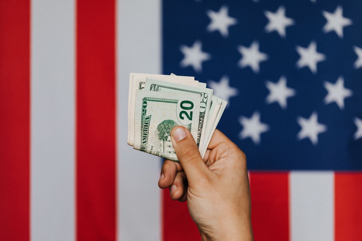 10 Harsh Reasons Middle-Class Californians Are Dropping Health Insurance 1 Unrecognizable male demonstrating dollars before official flag of USA on background