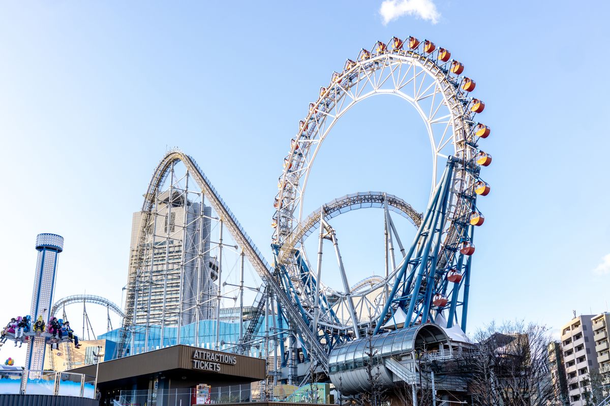 Vibrant Ferris wheel and roller coaster at Tokyo Dome City amusement park during daytime.