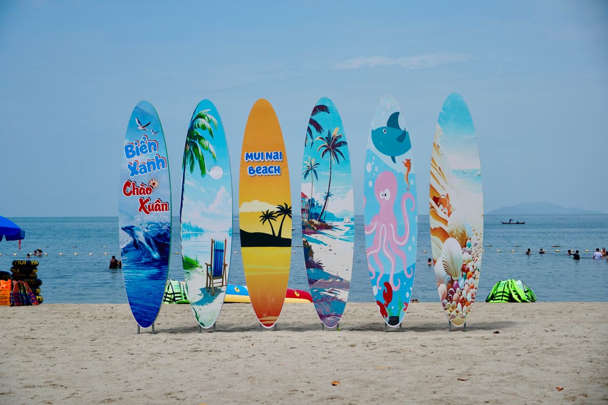 USA Tourist Boards Guide: The Smarter Way to Plan Your American Trip Using Local Experts 1 Vibrant surfboards with unique designs lined up on a sandy beach by the ocean.