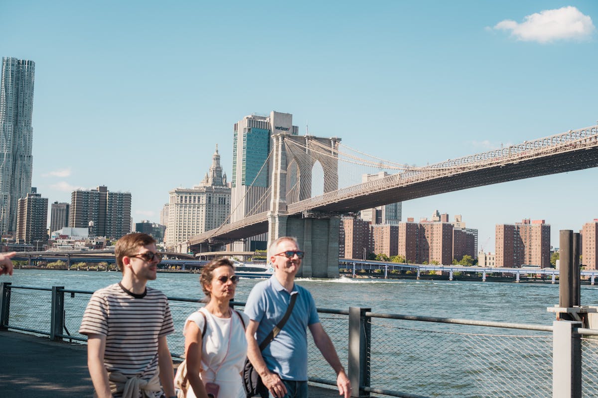 7 Disgusting American Habits That Make the Whole World Despise You 2 Visitors enjoy a sunny day walking near the iconic Brooklyn Bridge in New York City.