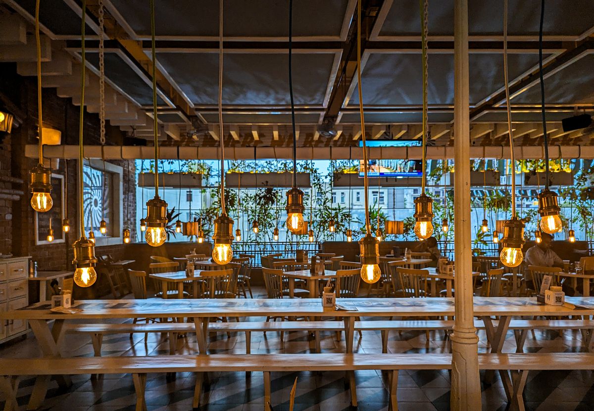 8 Restaurant Tricks Customers Rarely Notice 2 Warm, cozy indoor restaurant setting with hanging Edison bulbs in Bengaluru, India.
