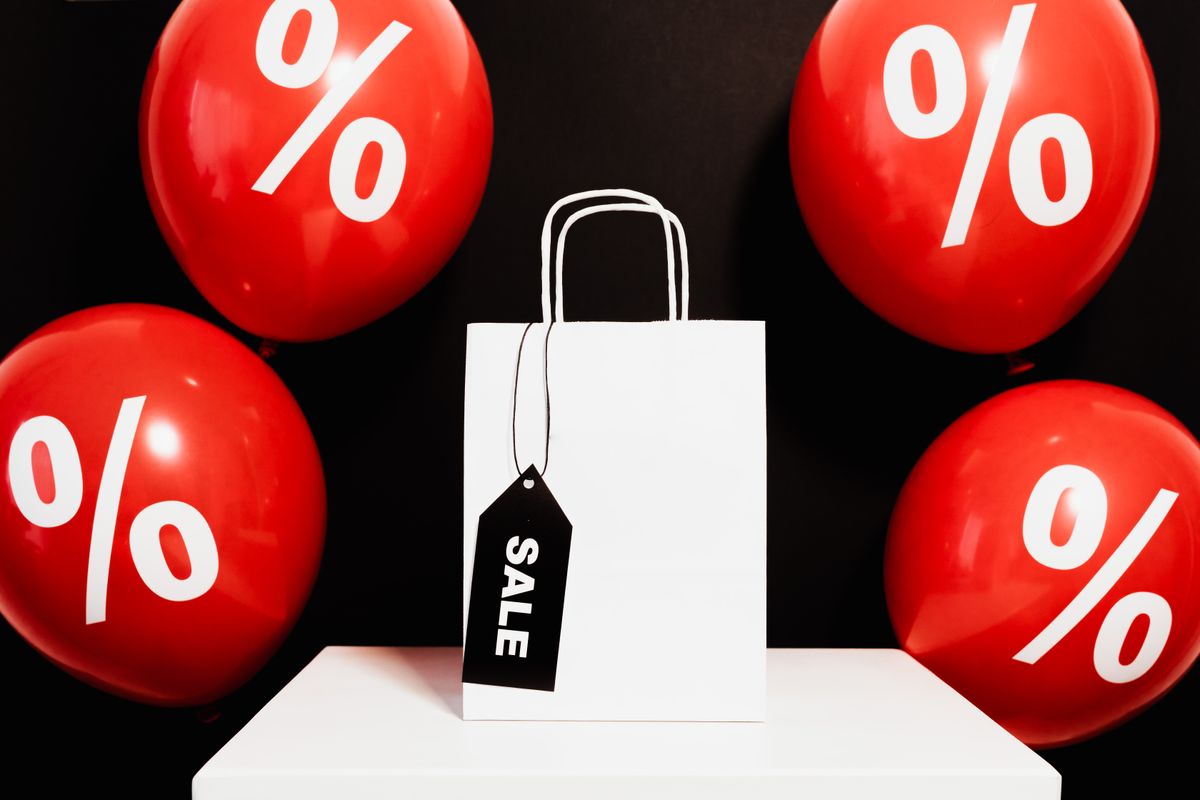 The “Anti-Designer Bag” Selling Fast at Nordstrom Is Nearly $50 Off. 1 White shopping bag with sale tag surrounded by red balloons displaying percentage signs.