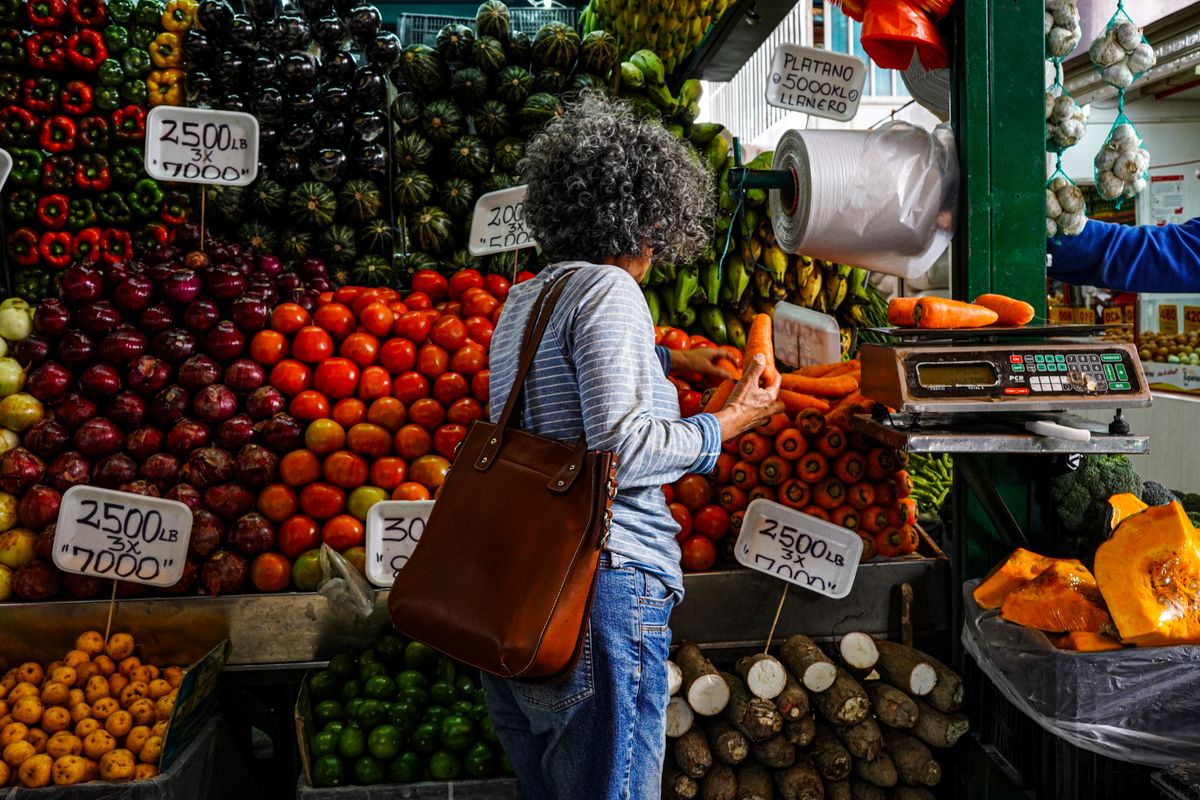 Data-Driven Strategies for Entering the African Market: A Modern Business Playbook 2 Woman shopping at a vibrant local market stall filled with fresh fruits and vegetables.