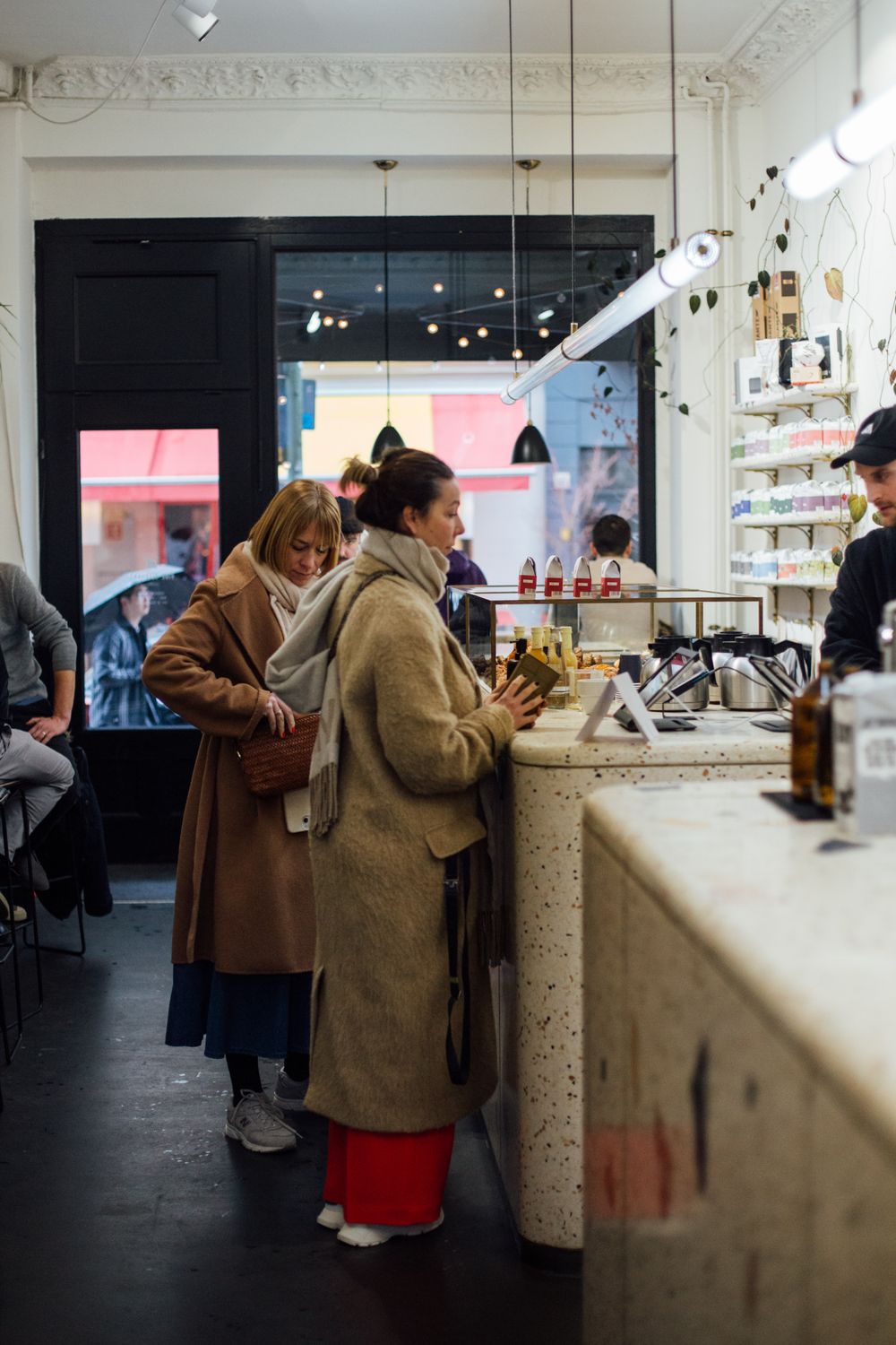 From Kitchen Idea to Thriving Brand: The Real Playbook for Starting a Food Business 3 Women in warm coats ordering at a stylish café counter in Berlin, Germany.