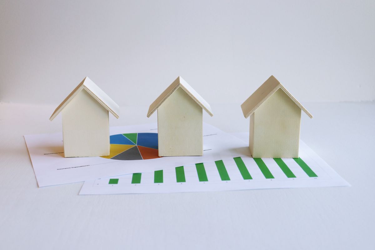 U.S. Housing Market Gains Momentum as Pending Home Sales Surge Despite High Mortgage Rates 2 Wooden model houses on graphs depict real estate market analysis and trends.
