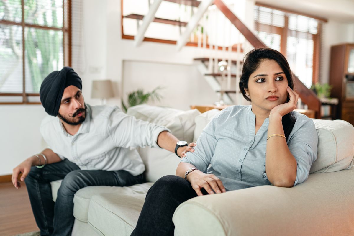 Young Indian man in turban and casual wear comforting frustrated wife during quarreling at home