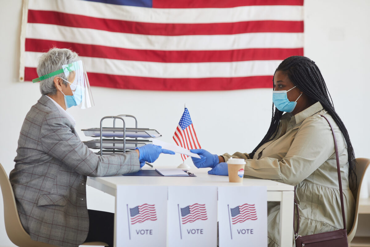 Side view portrait of young African-American woman wearing mask while registering for voting on post-pandemic election day, copy space