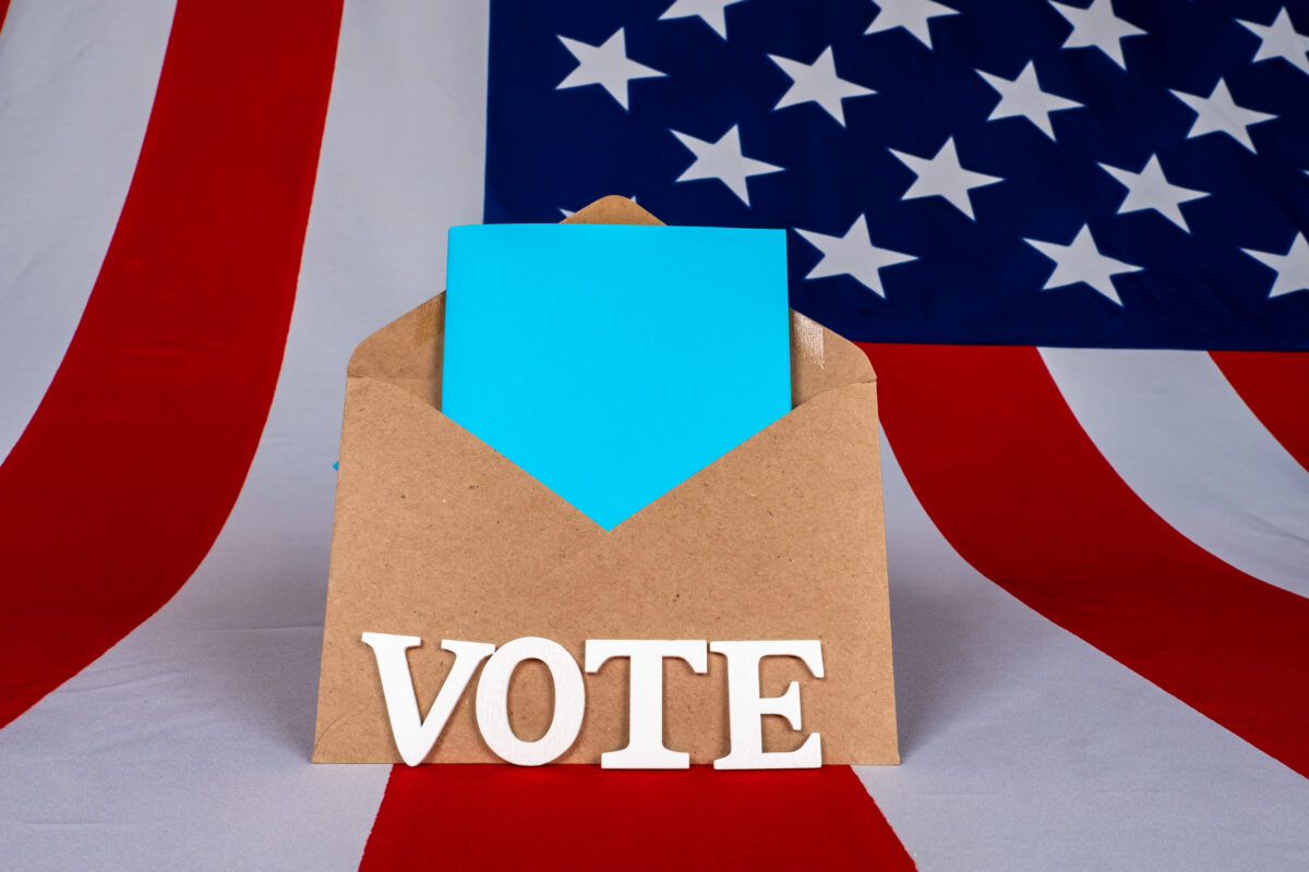 Trump’s Election Speech Ignites Fresh Impeachment Demand as Critics Warn of a 2026 Power Grab 2 Election vote by mail in USA. Envelope on background of USA flag. The vote logo next to mailing envelope. election vote of President of America. Absentee voting through postal service.
