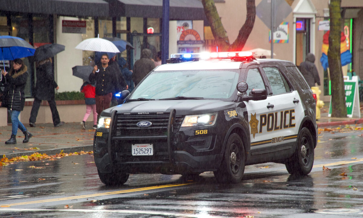 Benicia, CA - Dec 10, 2022: Police cruiser leading the annual Christmas Parade, featuring local marching bands, dancers, and the much anticipated Santa Claus. Walking in the rain.