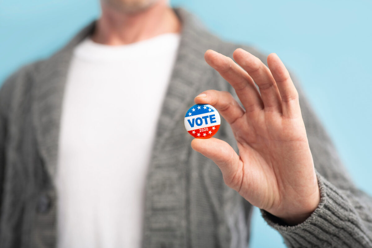 Law abiding american citizen holding vote pin in hand