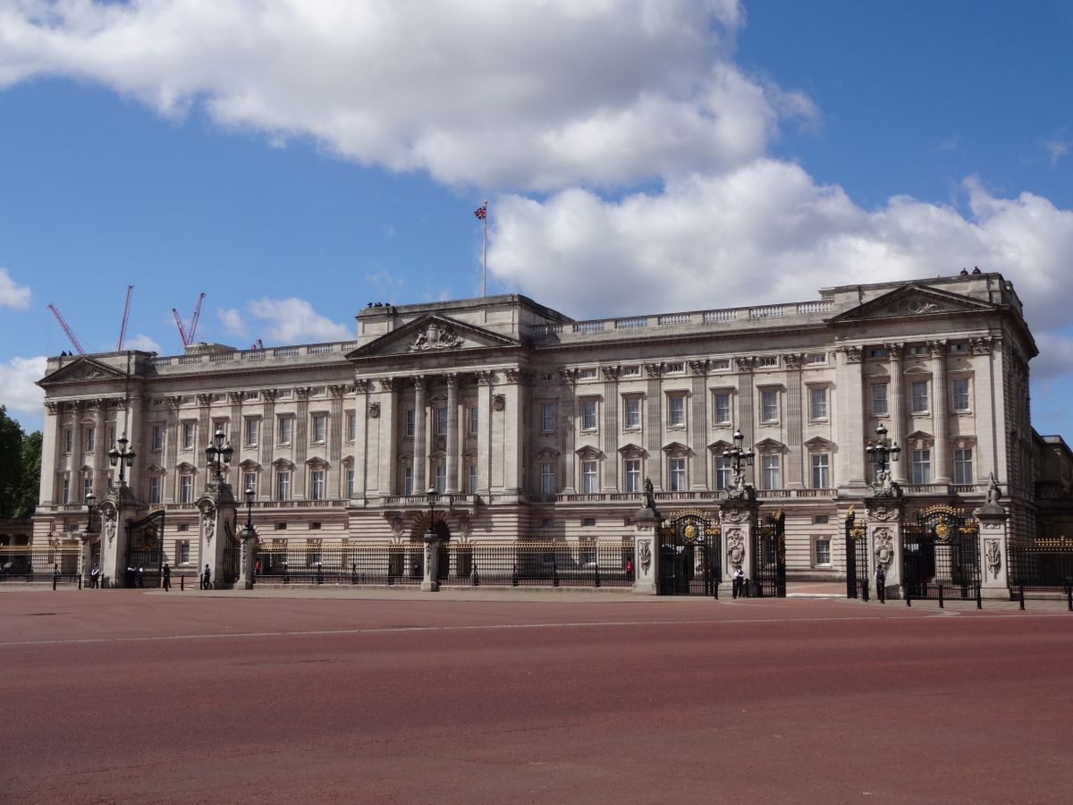 A clear view of Buckingham Palace in London with blue sky and clouds in the background.