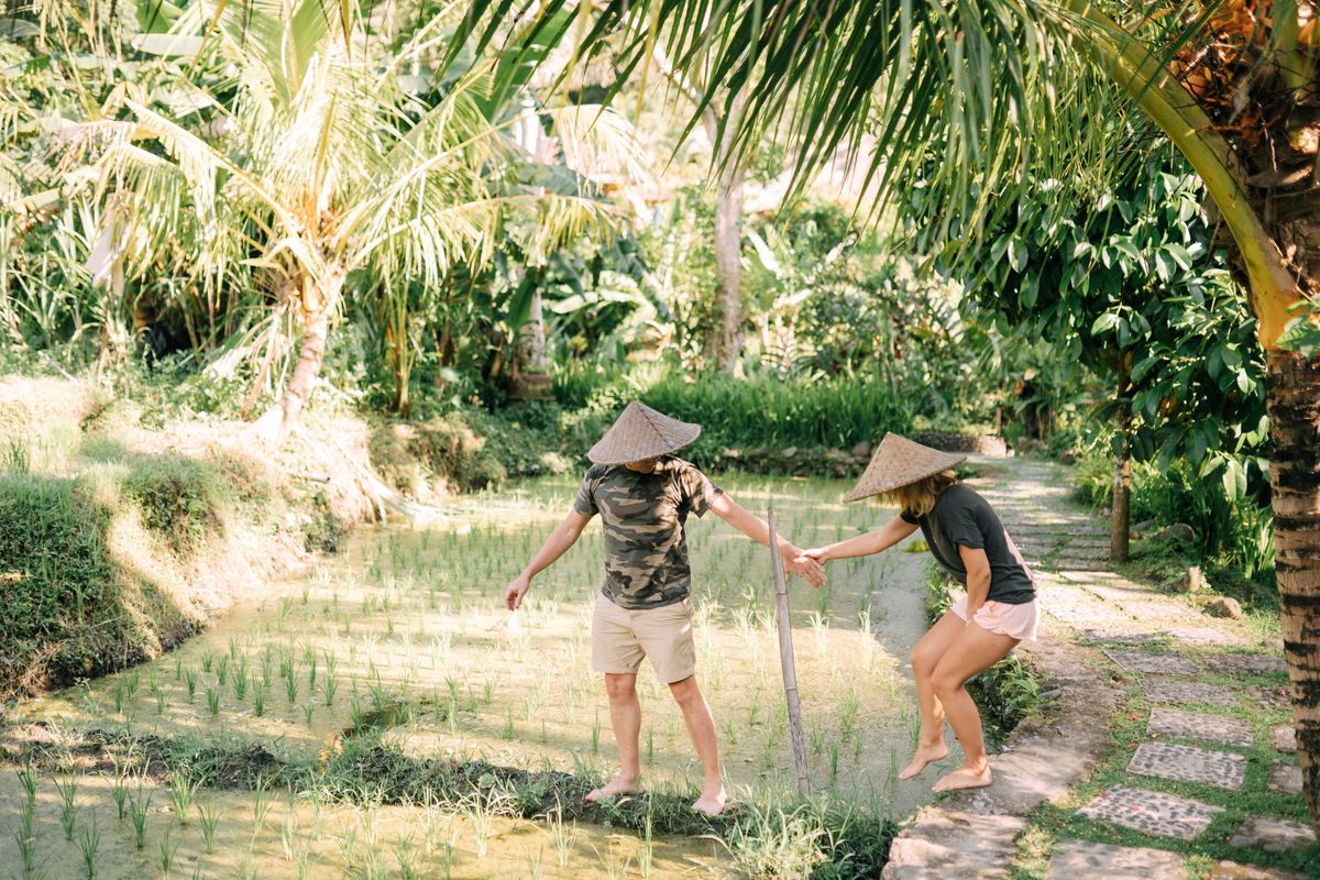 Types of Travelers Who Should Think Twice Before Booking an All-Inclusive Resort 2 A couple wearing straw hats walks through a lush tropical rice field.