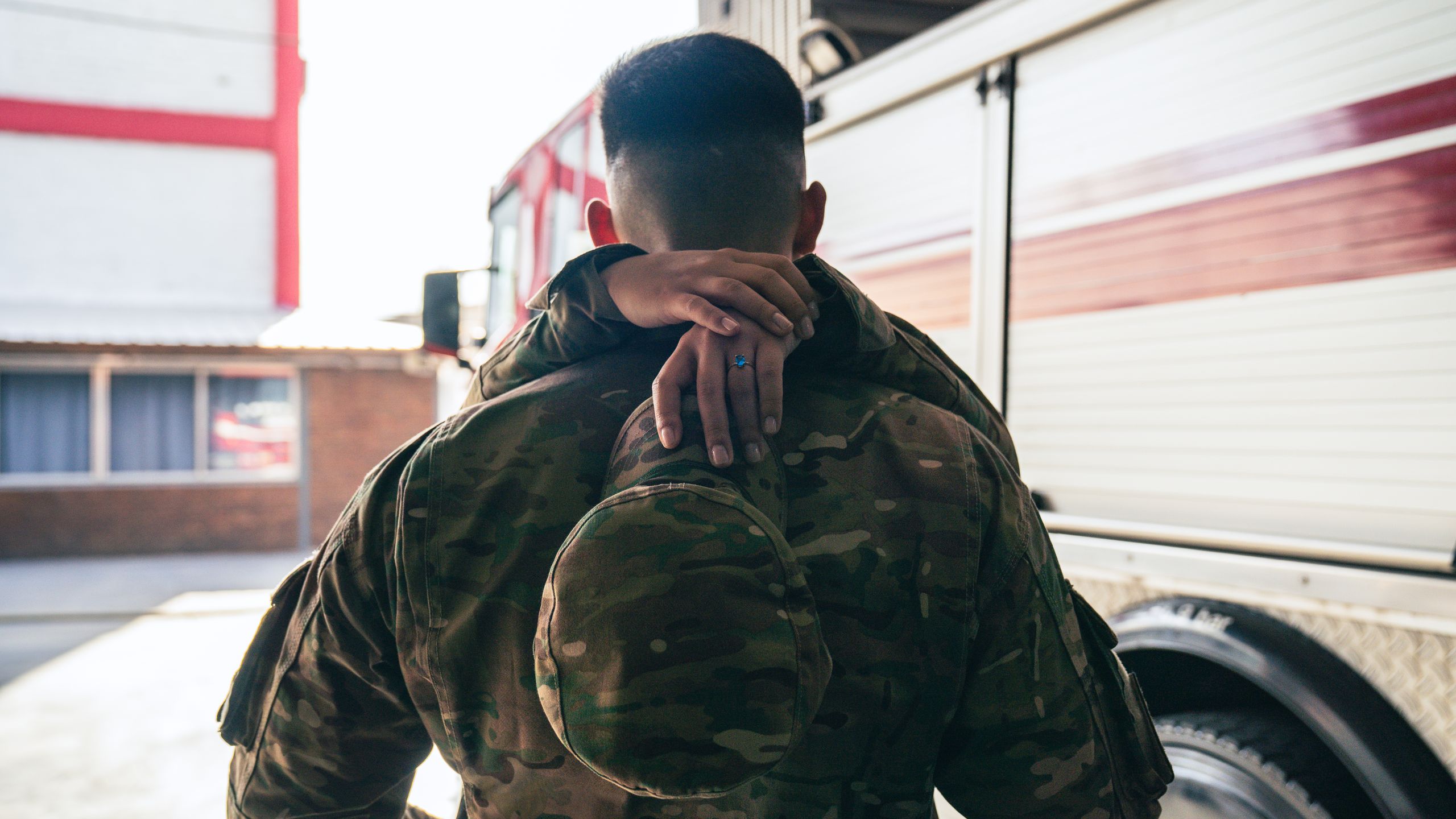 Army Captain Sentenced to 12 Years After Pregnant Soldier Was Secretly Given Abortion Drug 1 A heartfelt military reunion showing a soldier in uniform hugged from behind with a fire truck in the background.