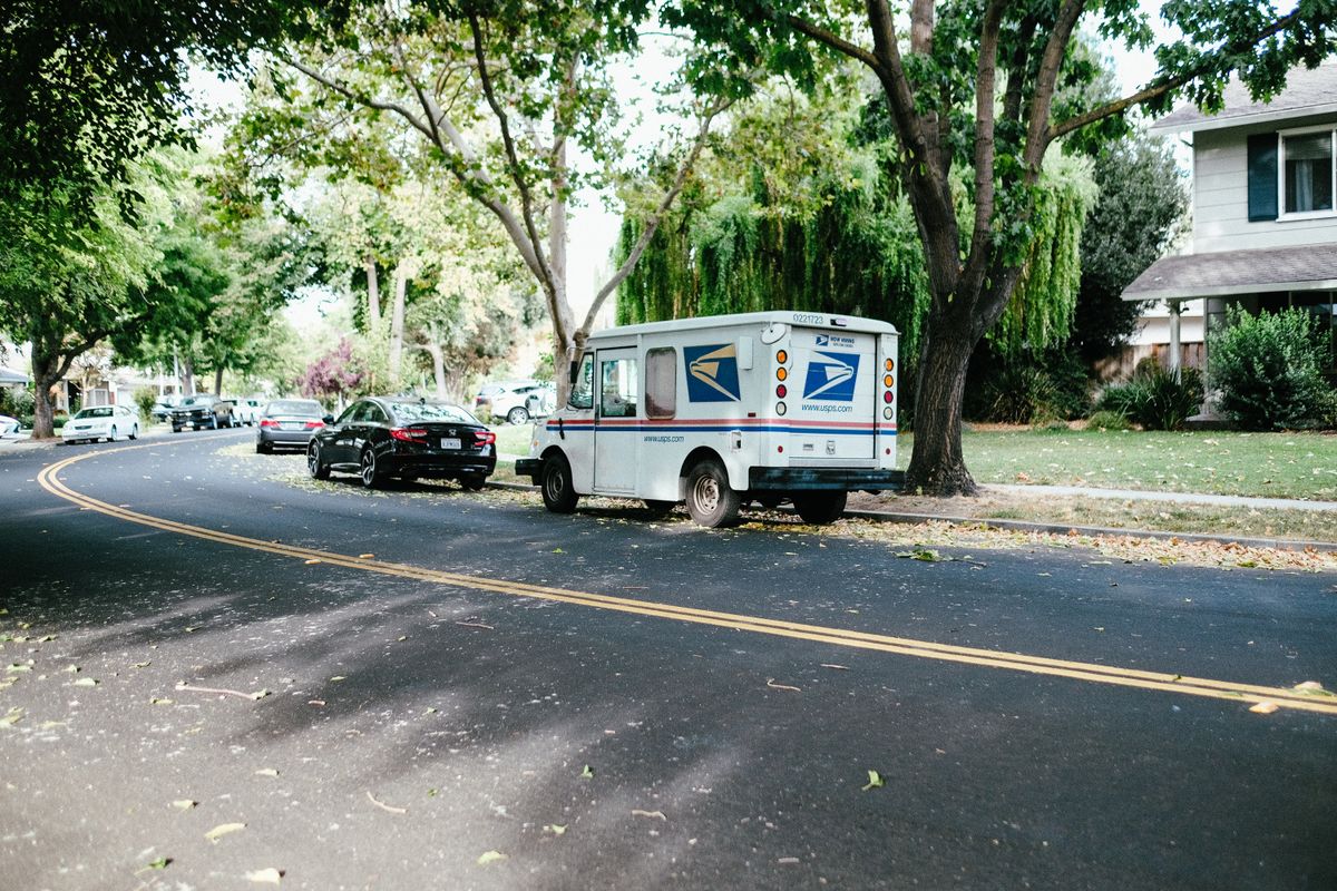 North Carolina postal worker Brandi Reynolds was killed while delivering mail in Hays County. 3 A postal delivery van parked on a tree-lined suburban street, showcasing daily mail service.