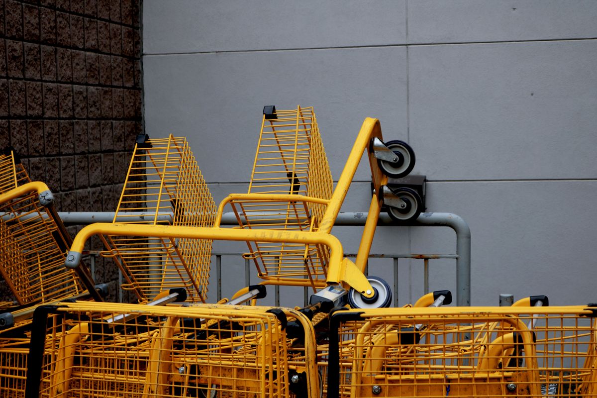 Walmart Shopping Cart Fee Sparks Debate As New $50 Charge Could Fund Community Programs. 1 A stack of yellow shopping carts outside a building, showcasing industrial design.