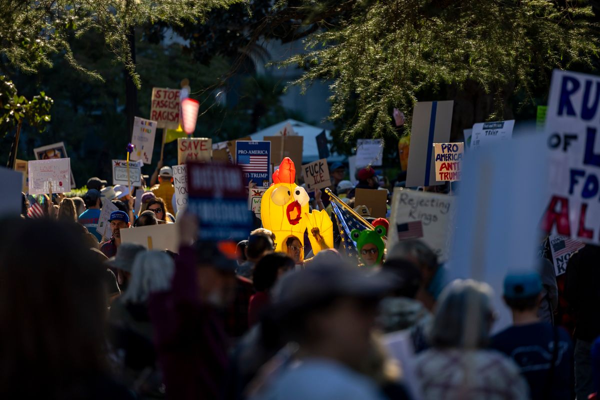 Alex Jones Turns on Trump Over Iran War as Draft Fears, Impeachment Talk and GOP Divisions Explode 2 A vibrant protest scene capturing various signs and symbols in downtown Sacramento.