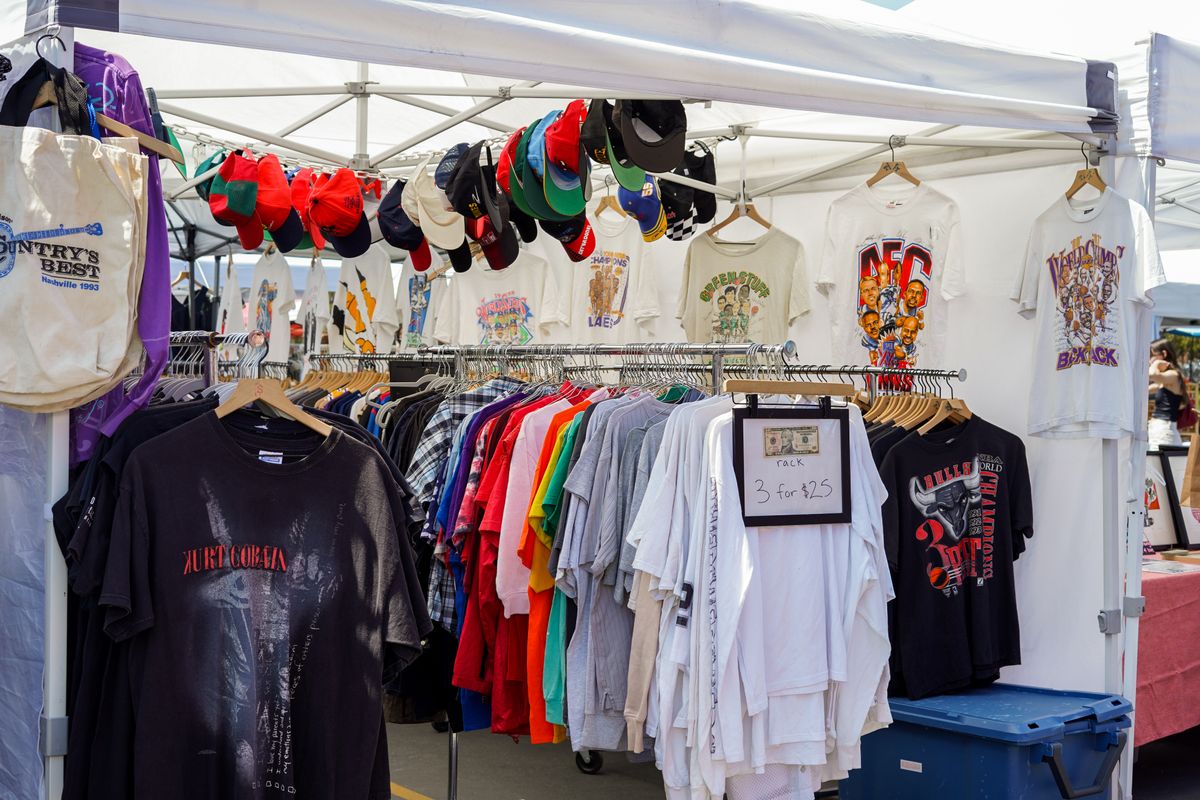 The Missing Trump Merchandise at the Great American State Fair and What It Really Signals 2 A vibrant street market stall featuring a variety of colorful t-shirts and caps under a tent.