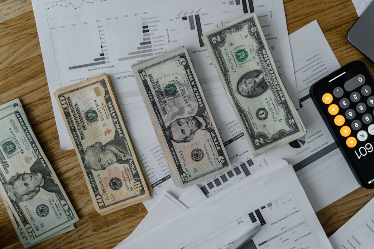 A workspace setup featuring cash, documents, and a calculator symbolizing financial analysis and budgeting.
