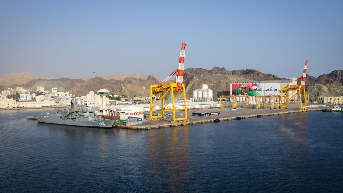 Aerial view of Muscat port with ship, cranes, and mountains in Oman.