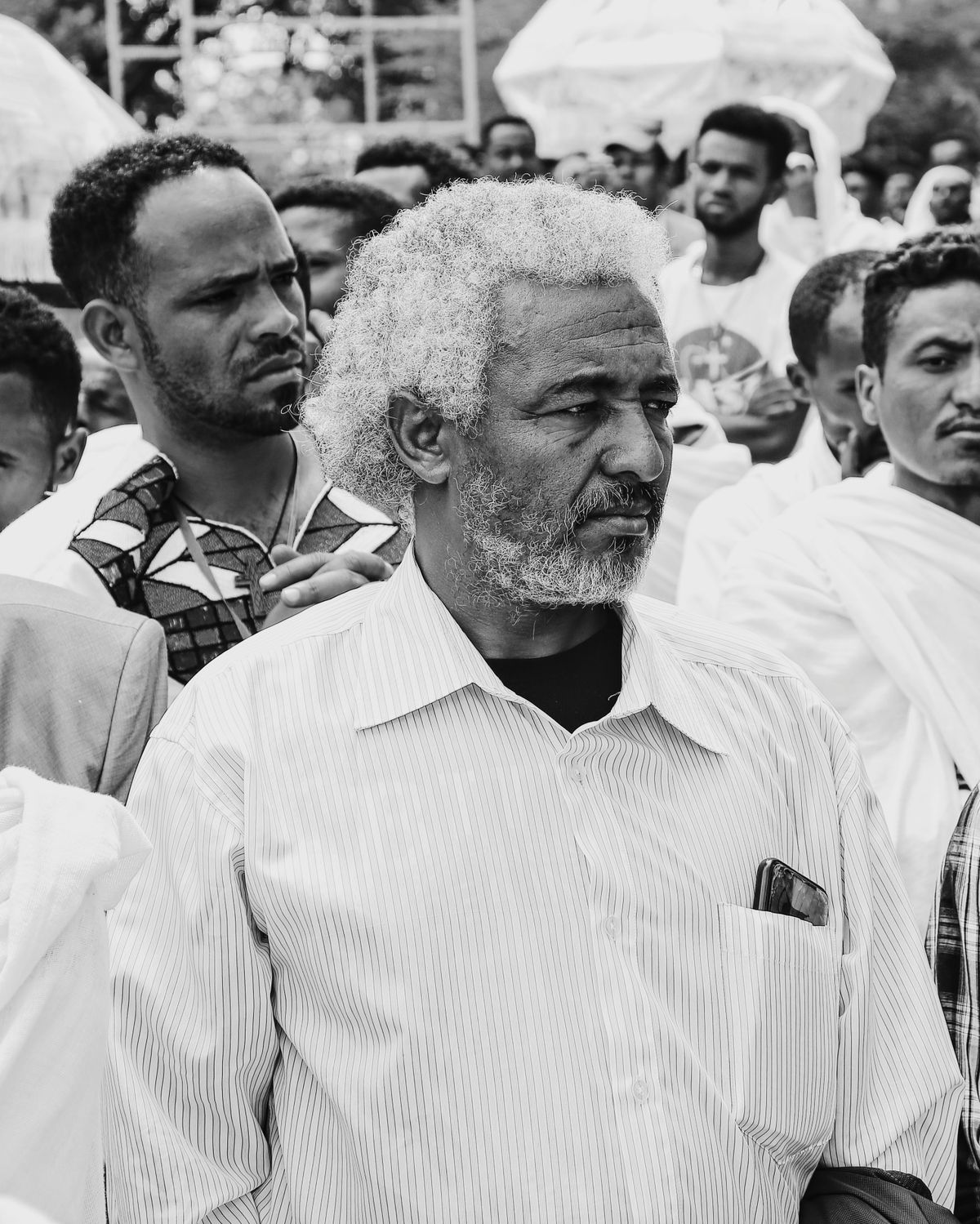 Black and white image capturing a group of Ethiopian men participating in a public gathering.