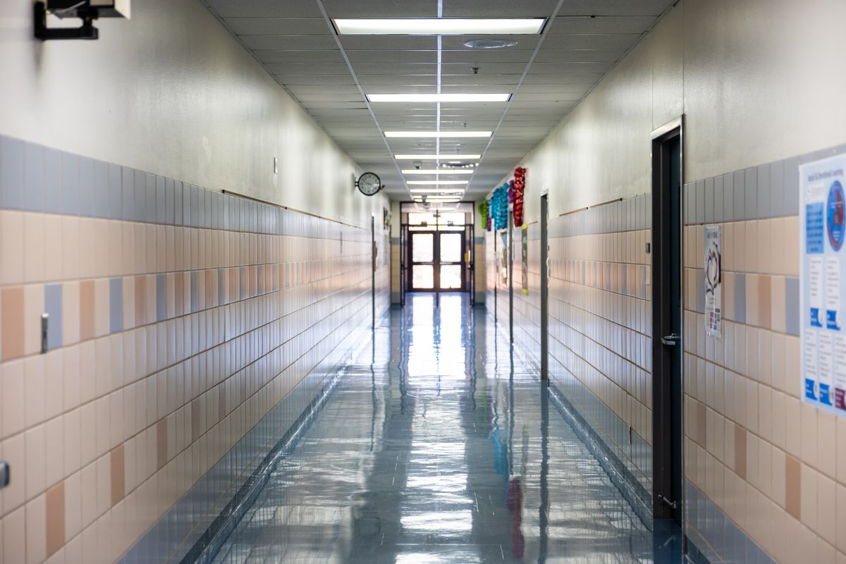 Bright, empty school hallway with fluorescent lighting, reflecting a clean, shiny floor.